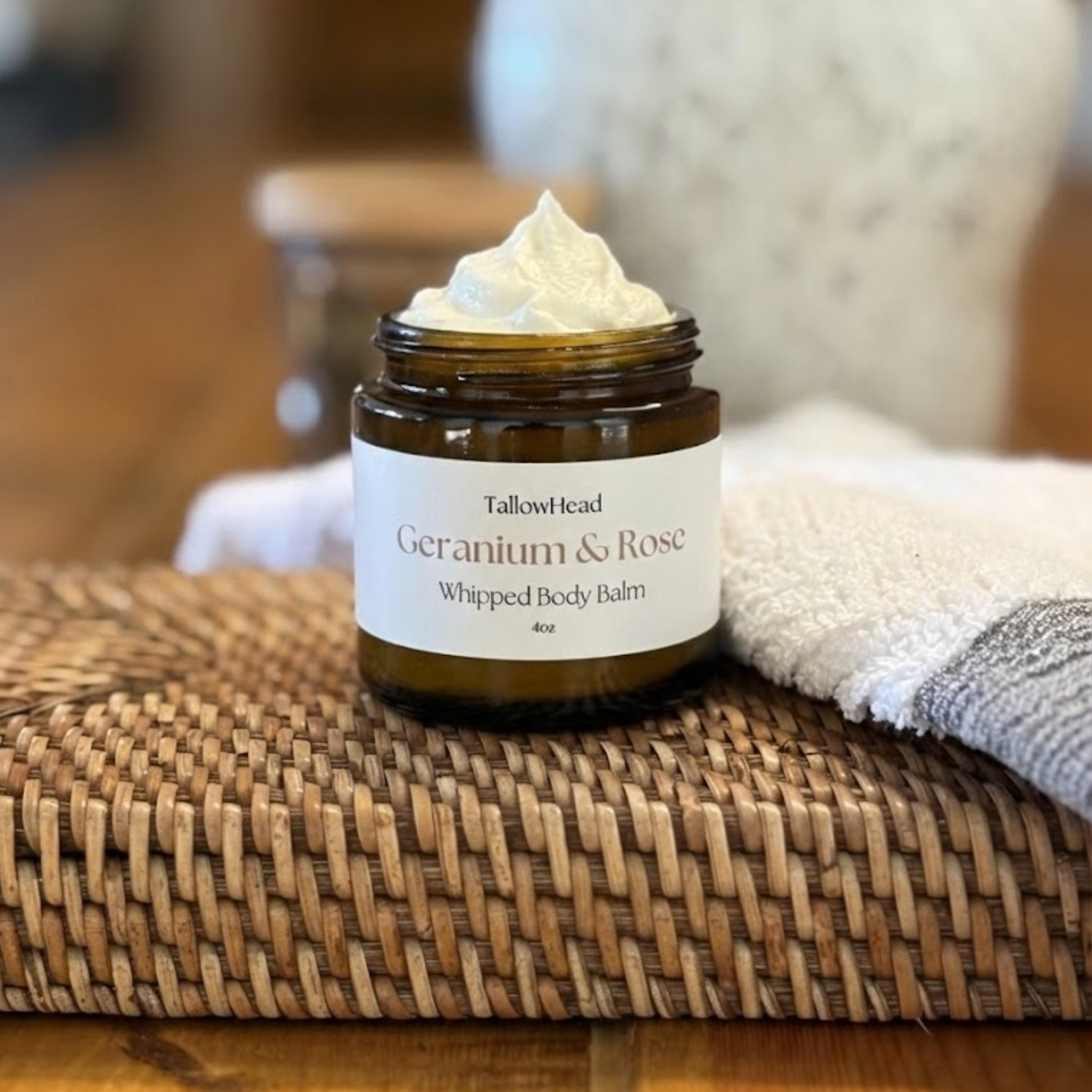 Jar of Tallow Geranium & Rose Whipped Body Balm on a woven mat with a blurred background