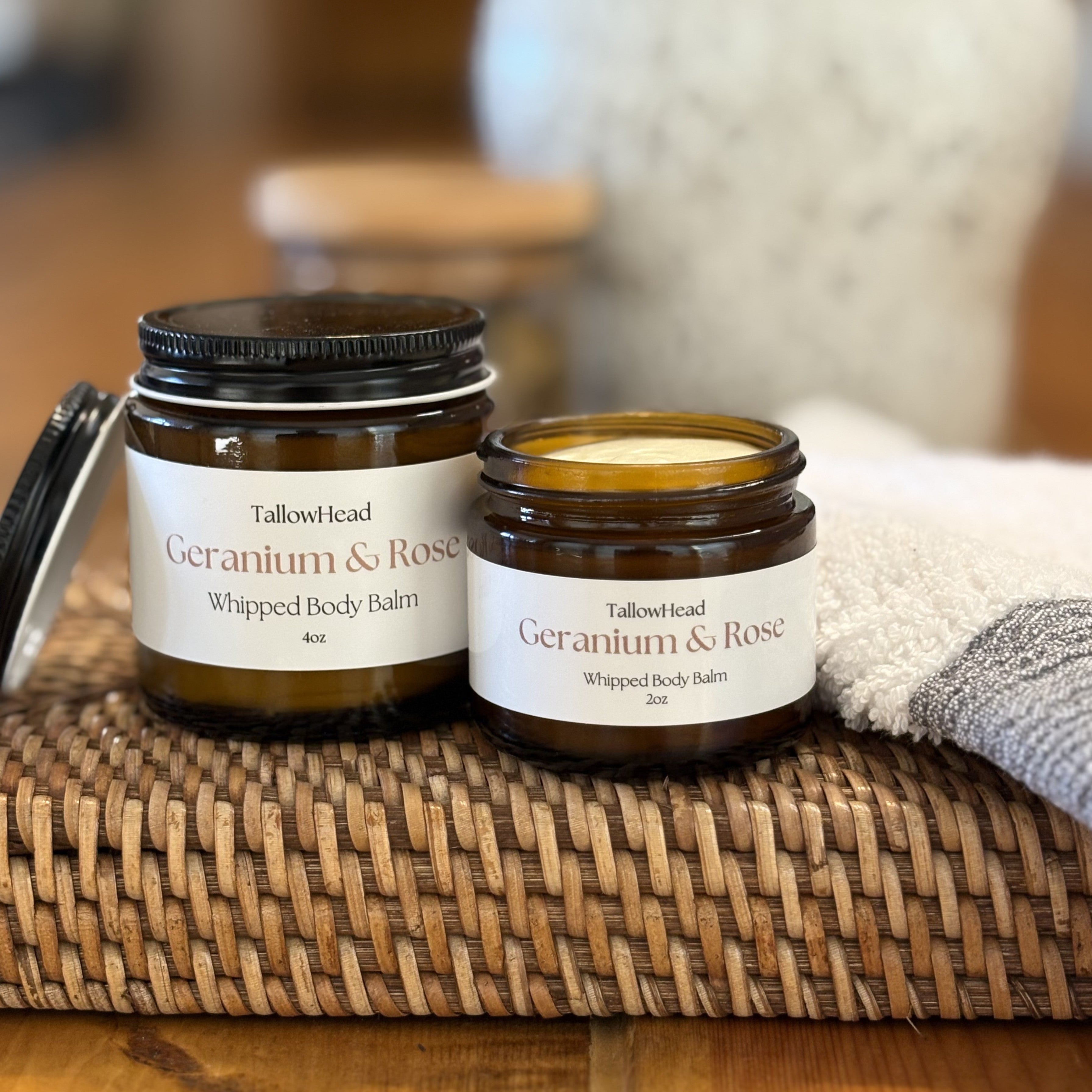 Two jars of Tallowhead Geranium & Rose whipped body balms on a woven mat with a blurred background.