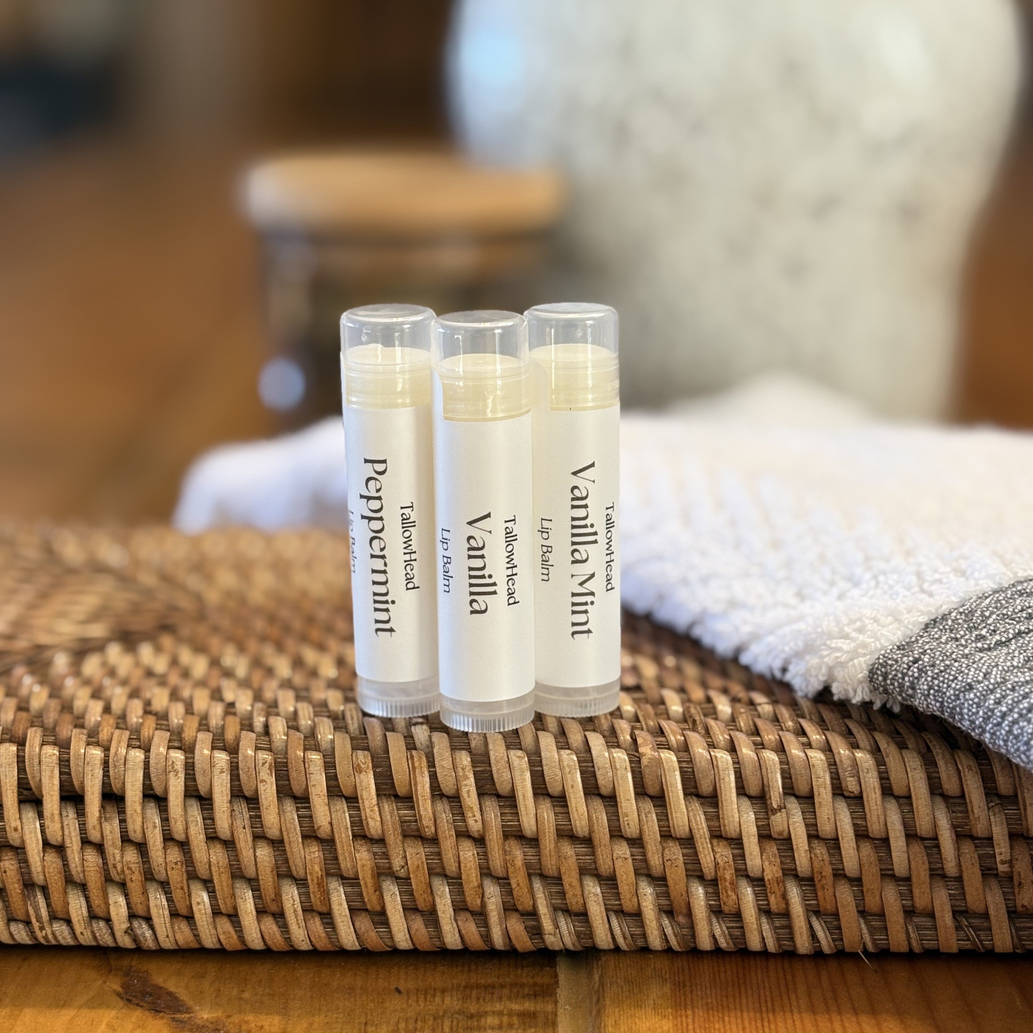 Three lip balm tubes on a woven surface with a blurred background