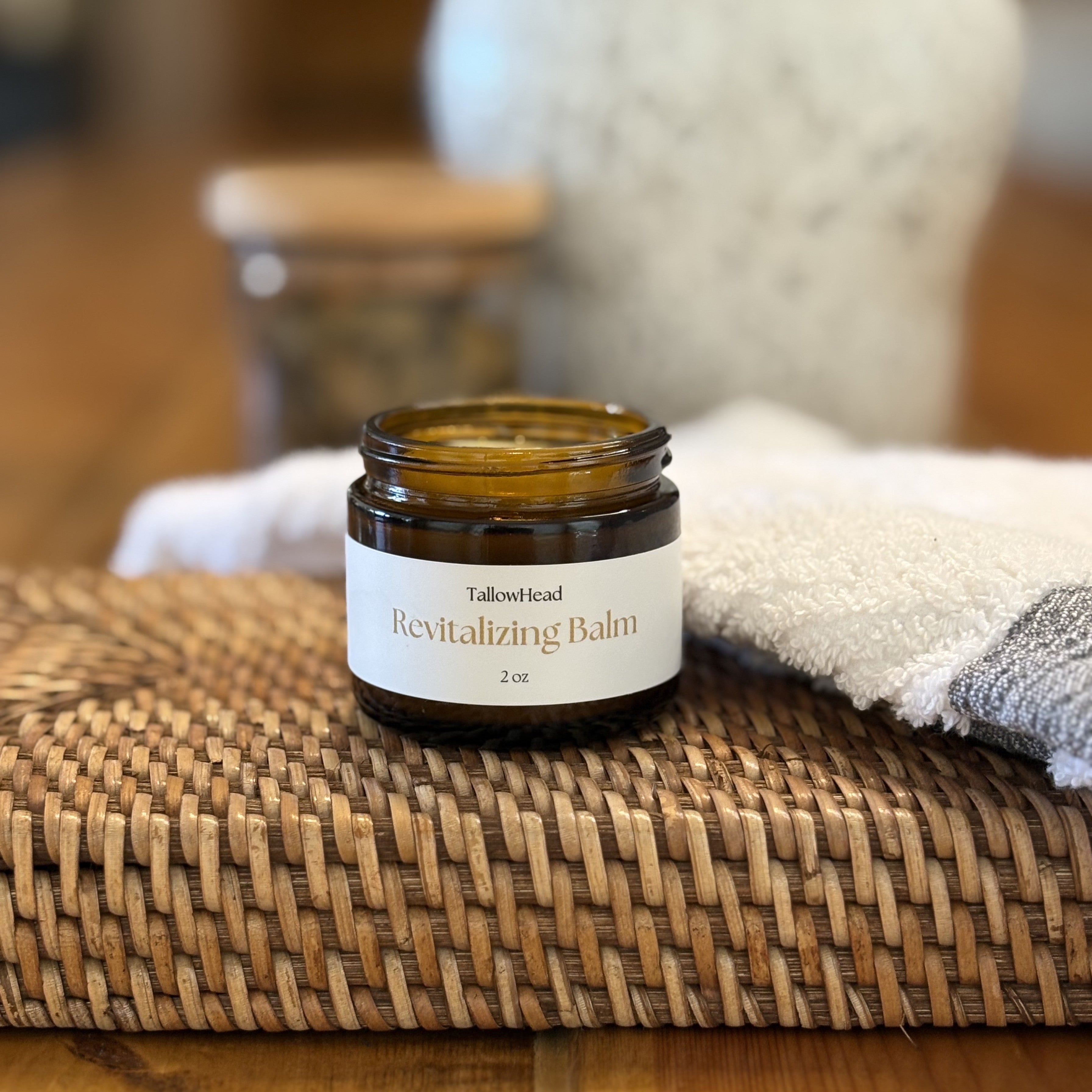 Jar of 'Revitalizing Balm' on a woven mat with a blurred background