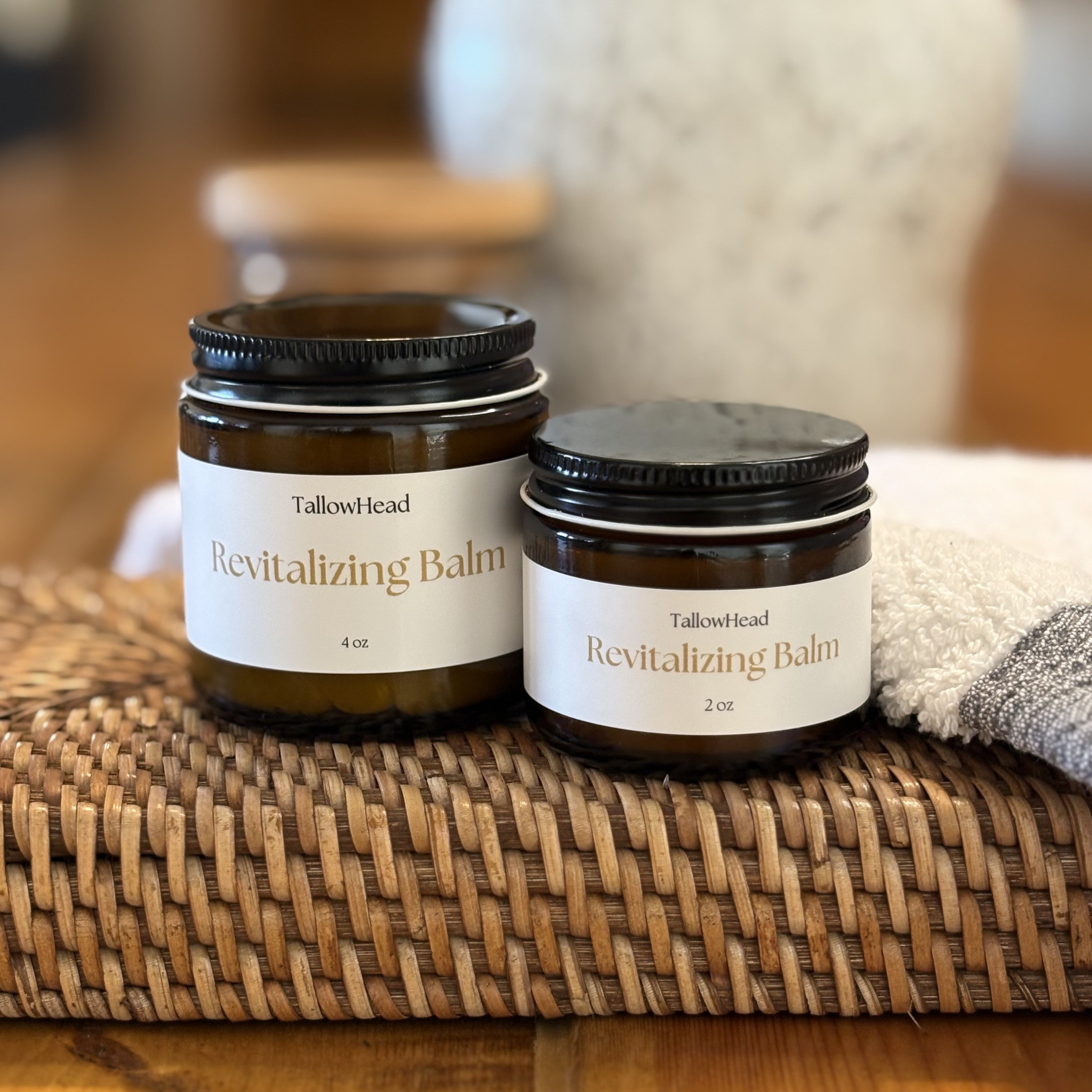Two jars of TallowHead Revitalizing Balm on a woven mat with a blurred background