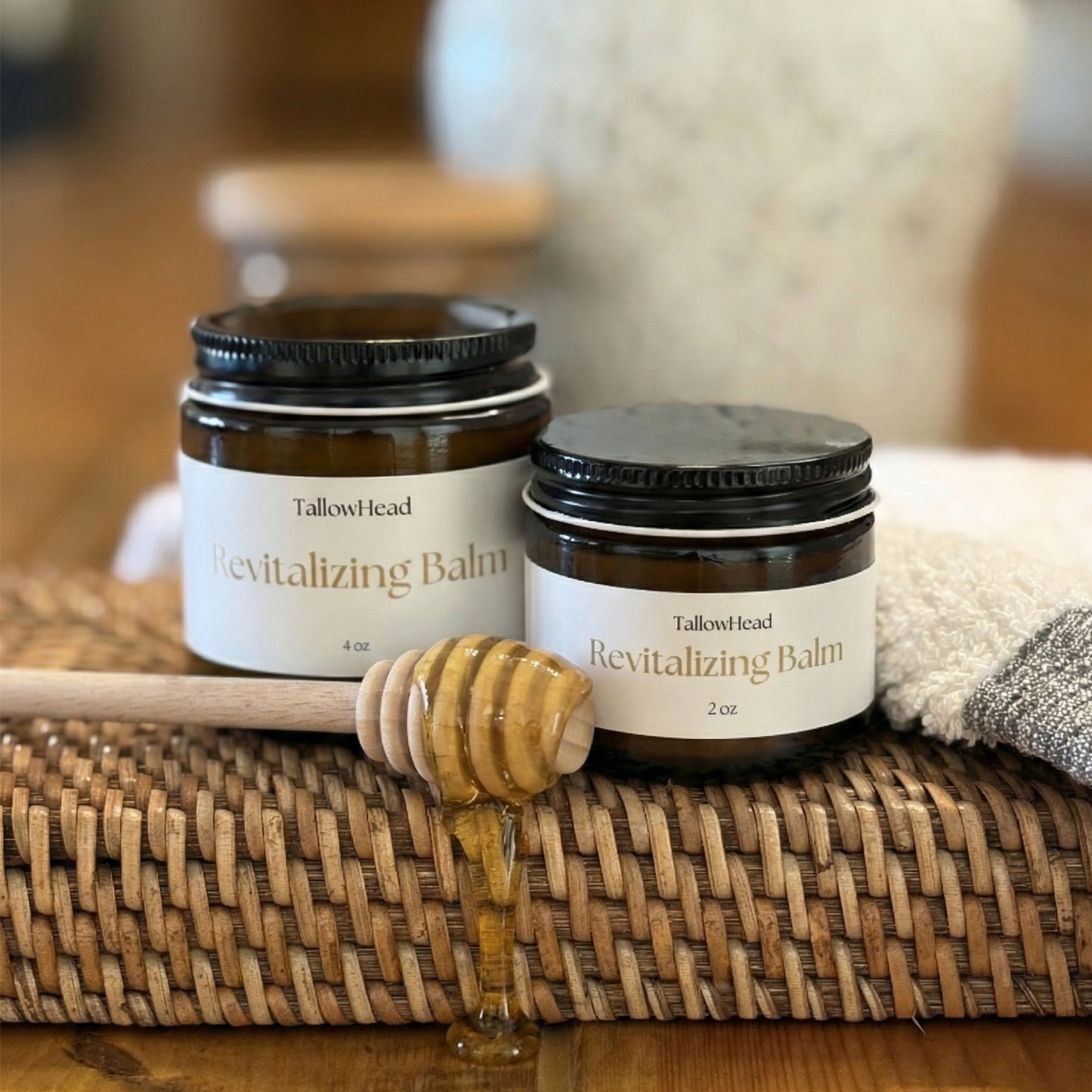 Two jars of Tallow Head Revitalizing Balm on a woven mat with honey and a wooden spoon.