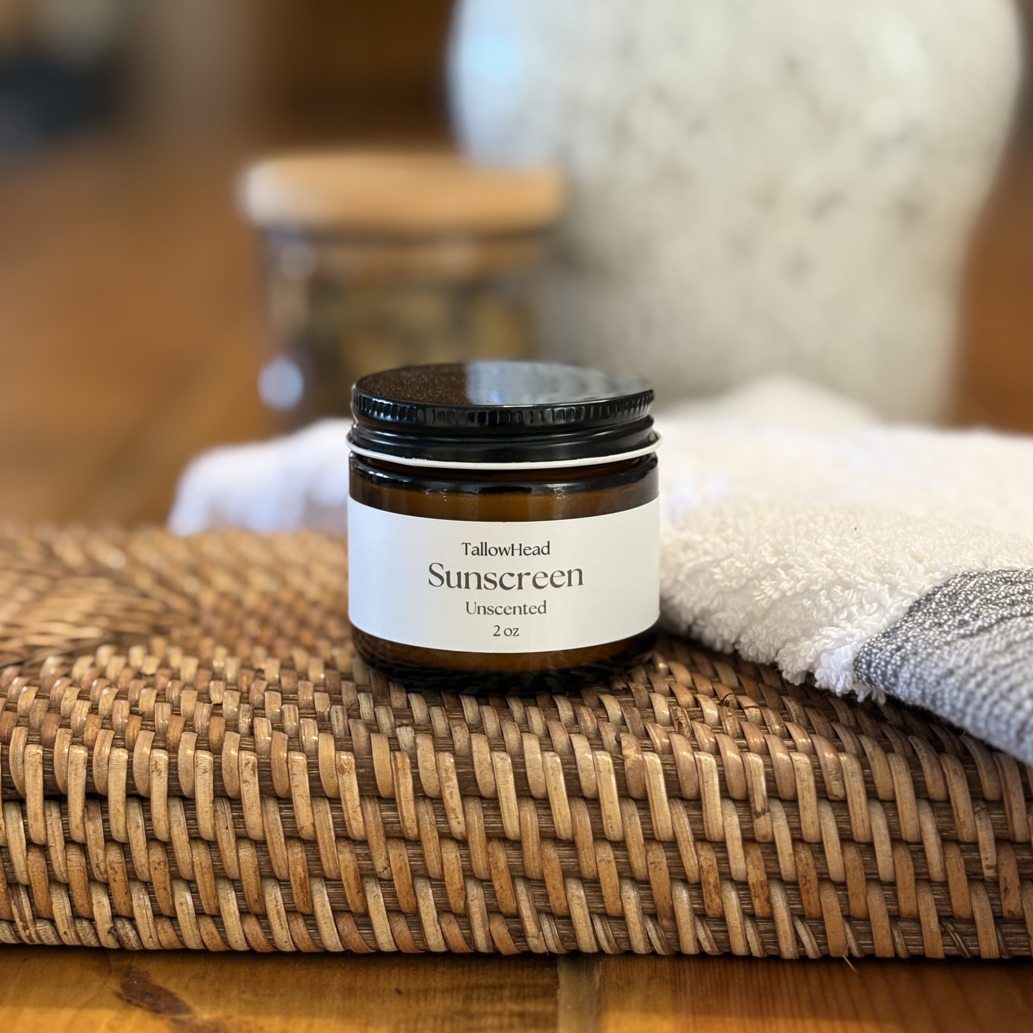 Small jar of sunscreen on a woven mat with a blurred background