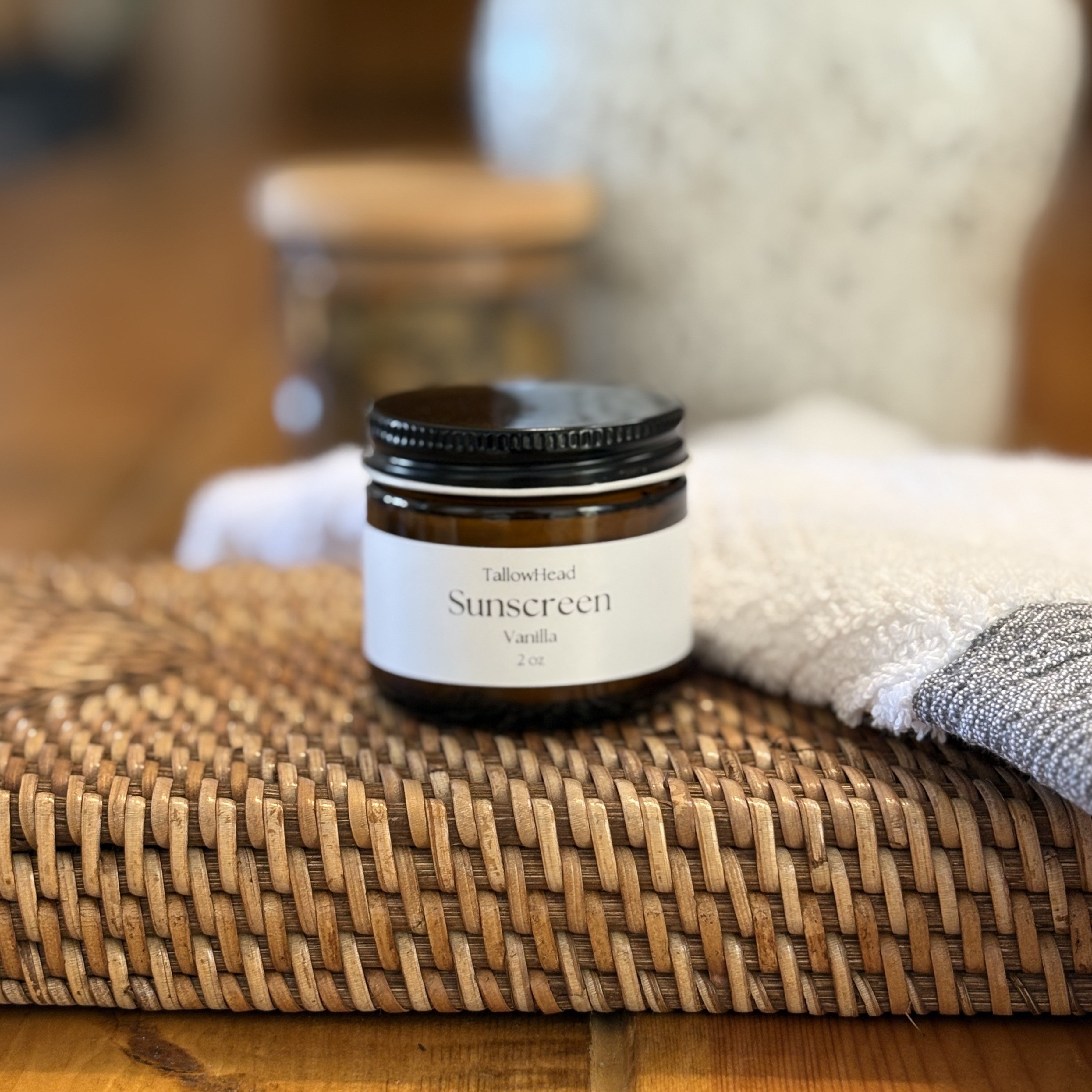 Small jar of sunscreen on a woven mat with a blurred background