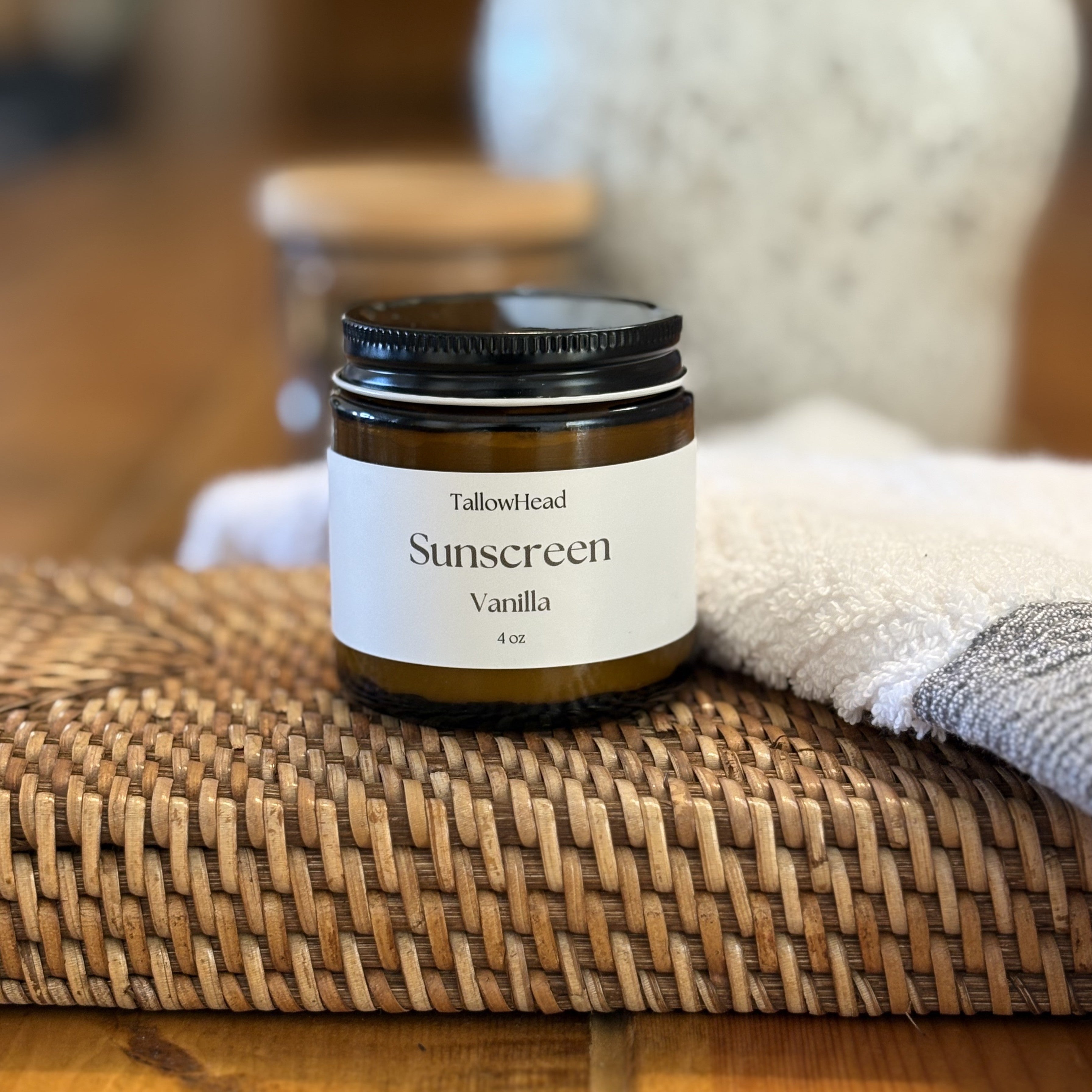 Sunscreen jar labeled 'Vanilla' on a woven mat with a blurred background