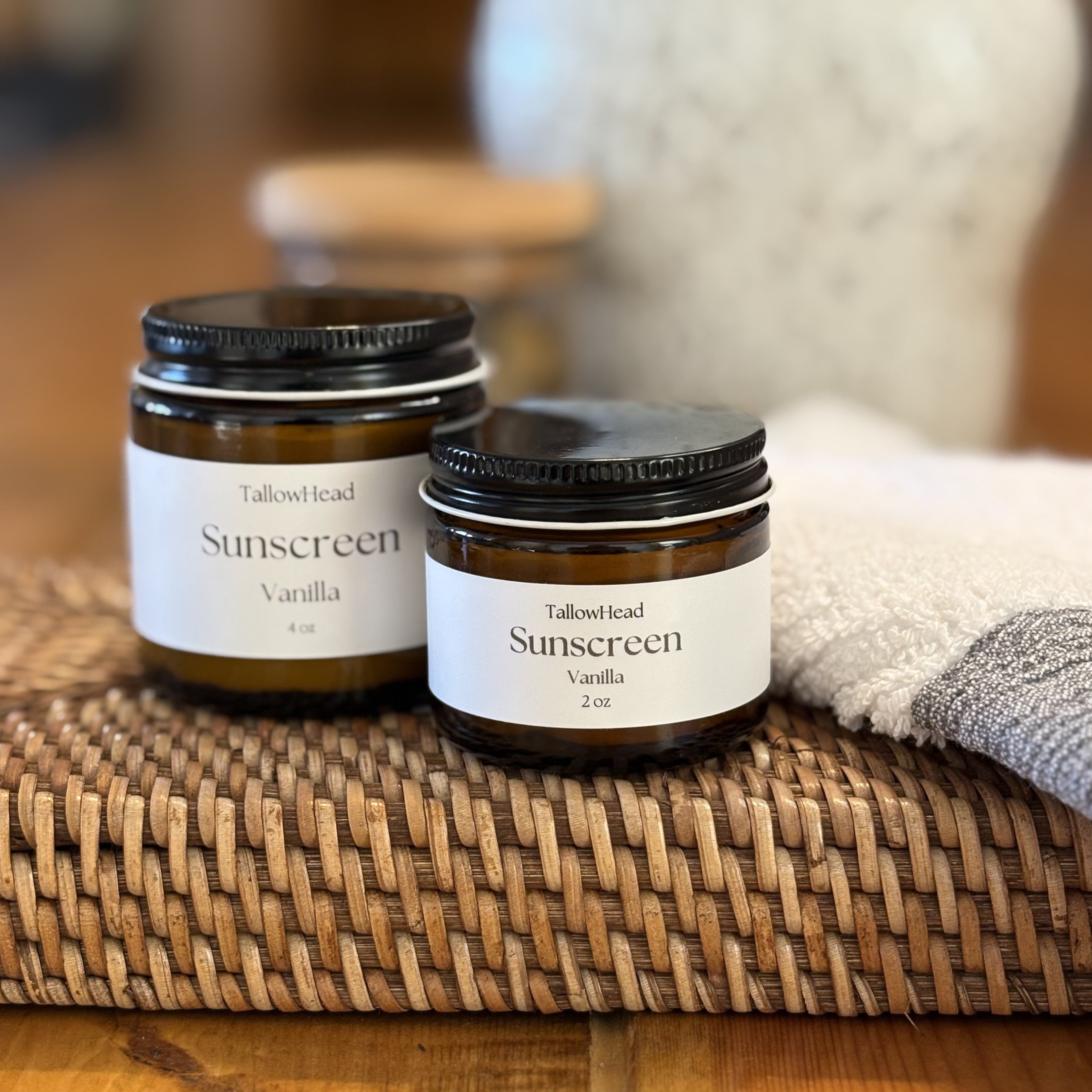 Two jars of Tallowhead Sunscreen Vanilla on a woven mat with a blurred background