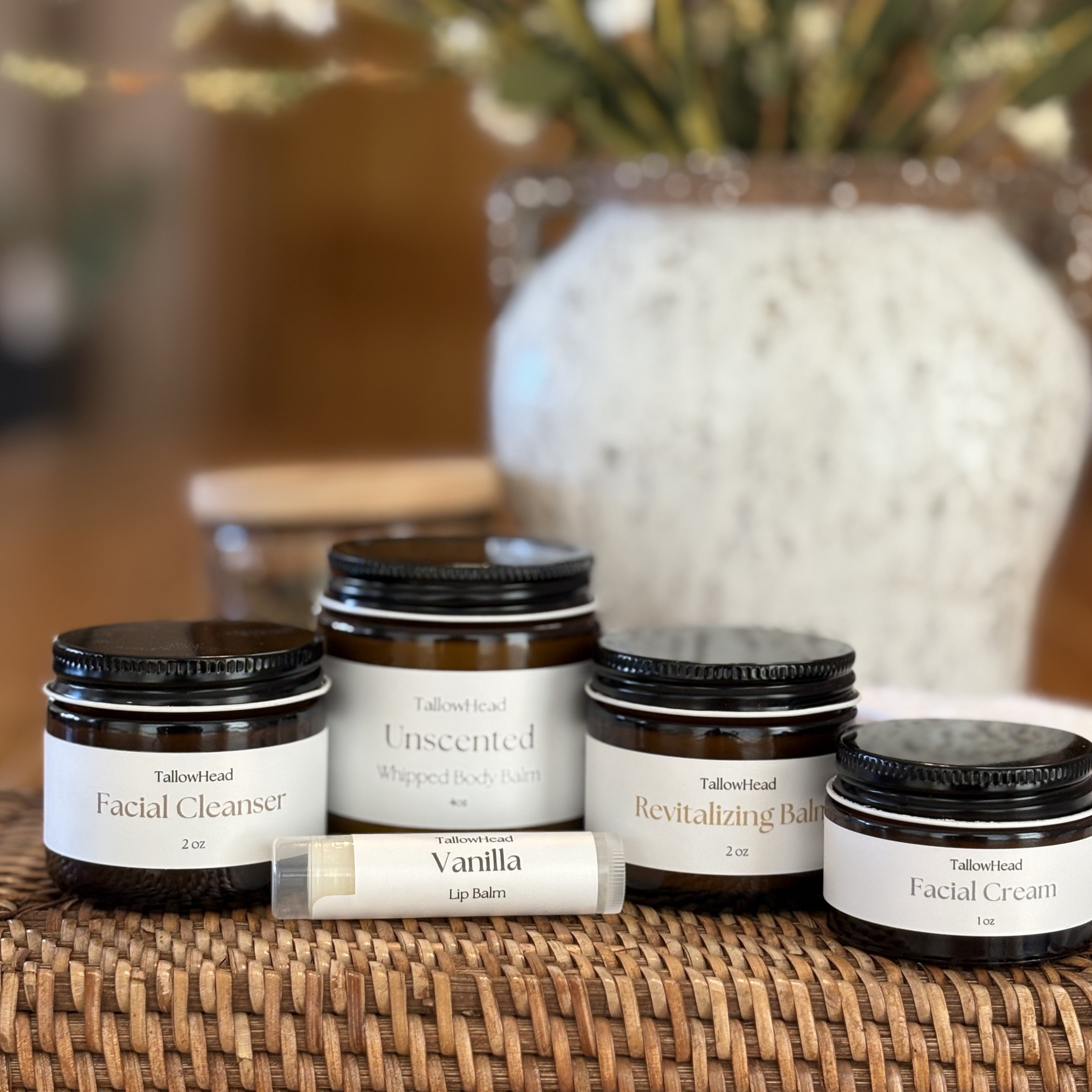 Collection of facial skincare products on a woven surface with a blurred decorative background.