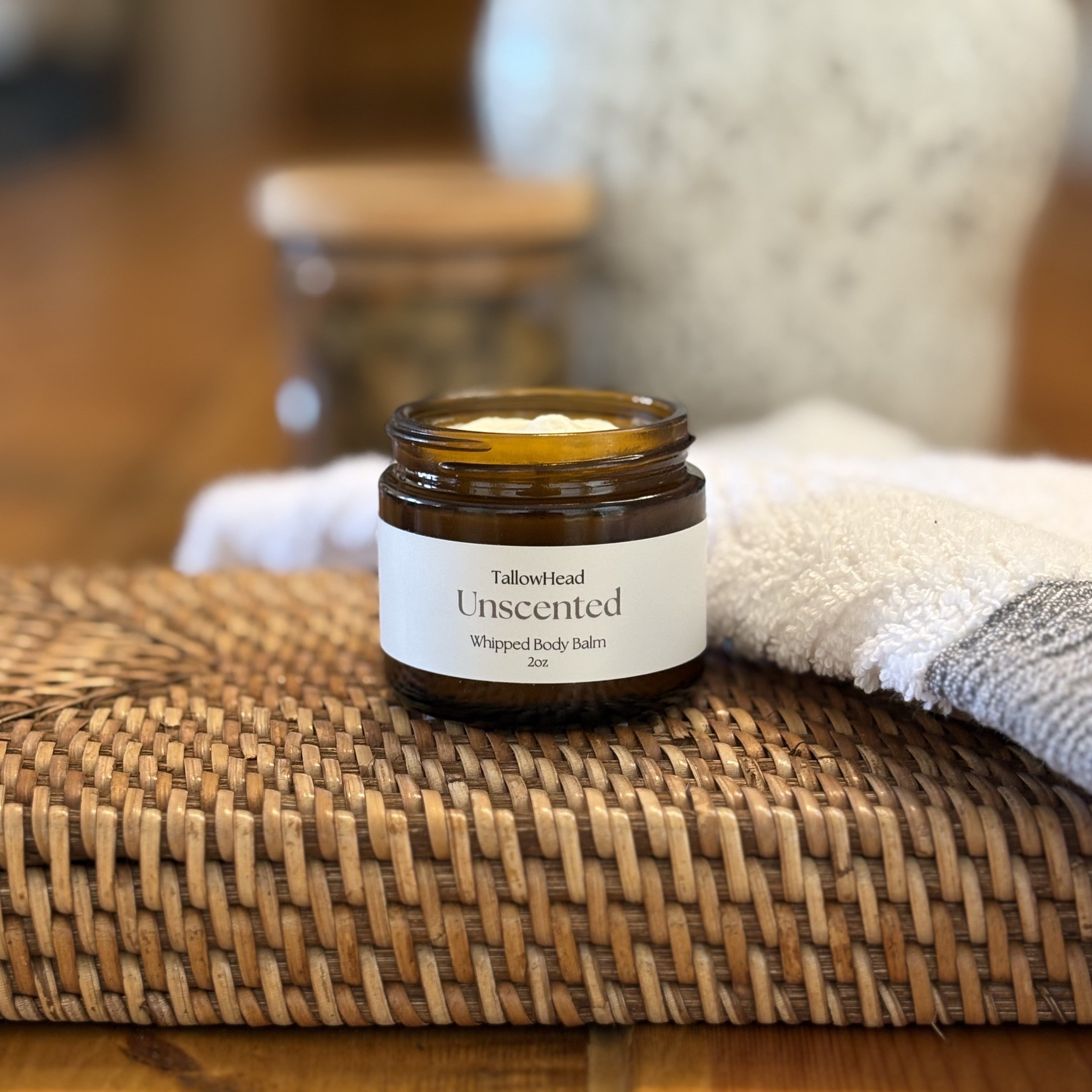 Jar of unscented whipped body balm on a woven mat with a blurred background