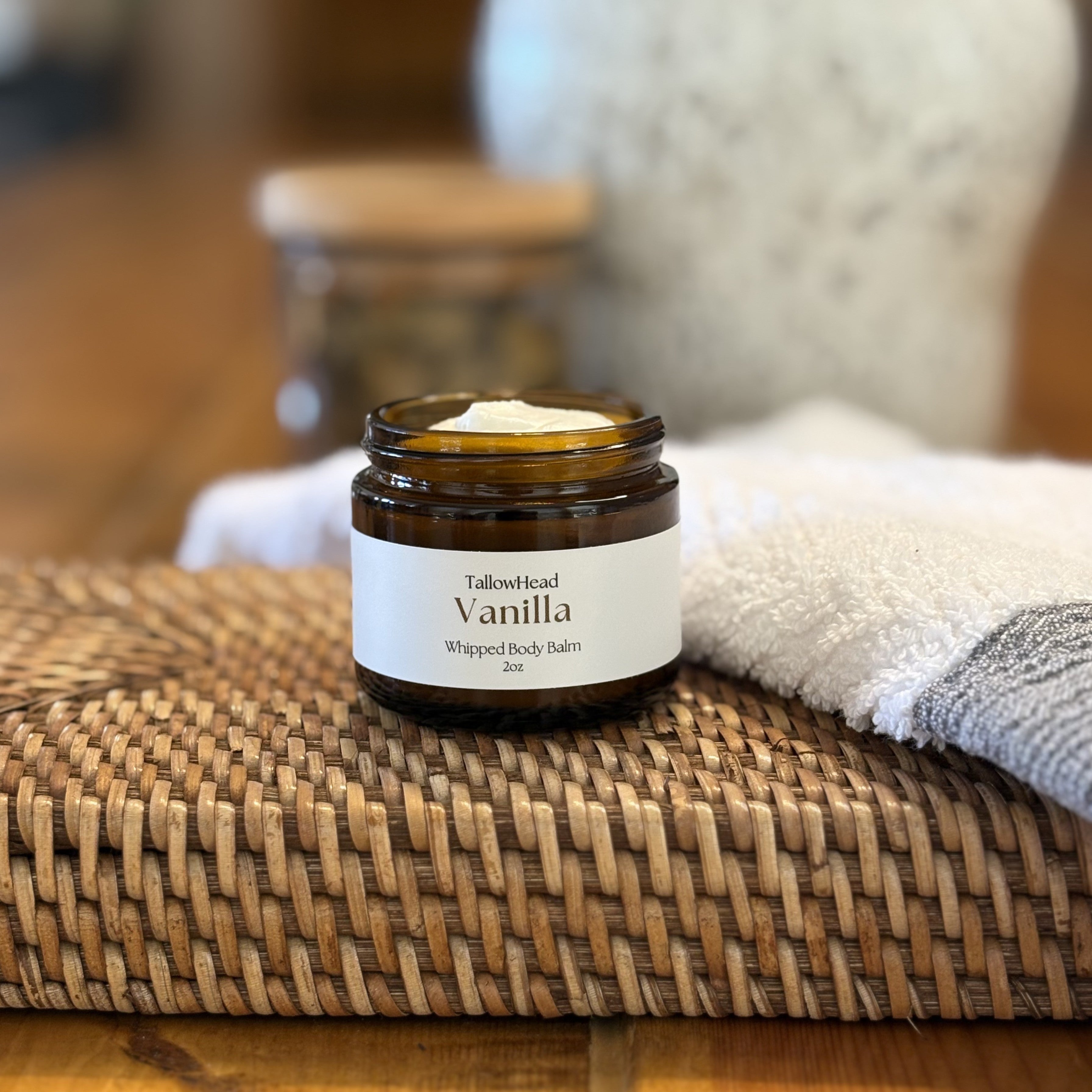 Jar of Vanilla whipped body balm on a woven mat with a blurred background