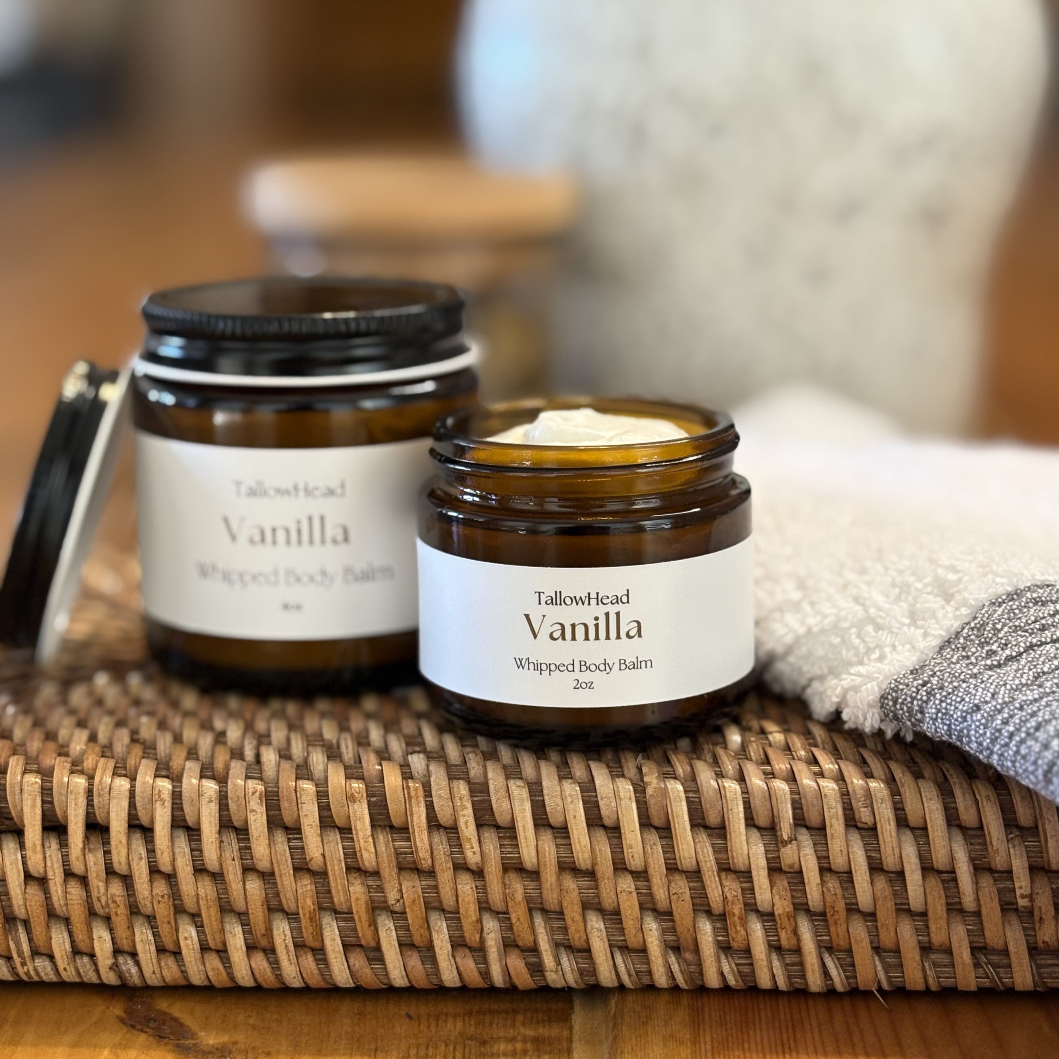 Two jars of Vanilla whipped body balm on a woven mat with a blurred background
