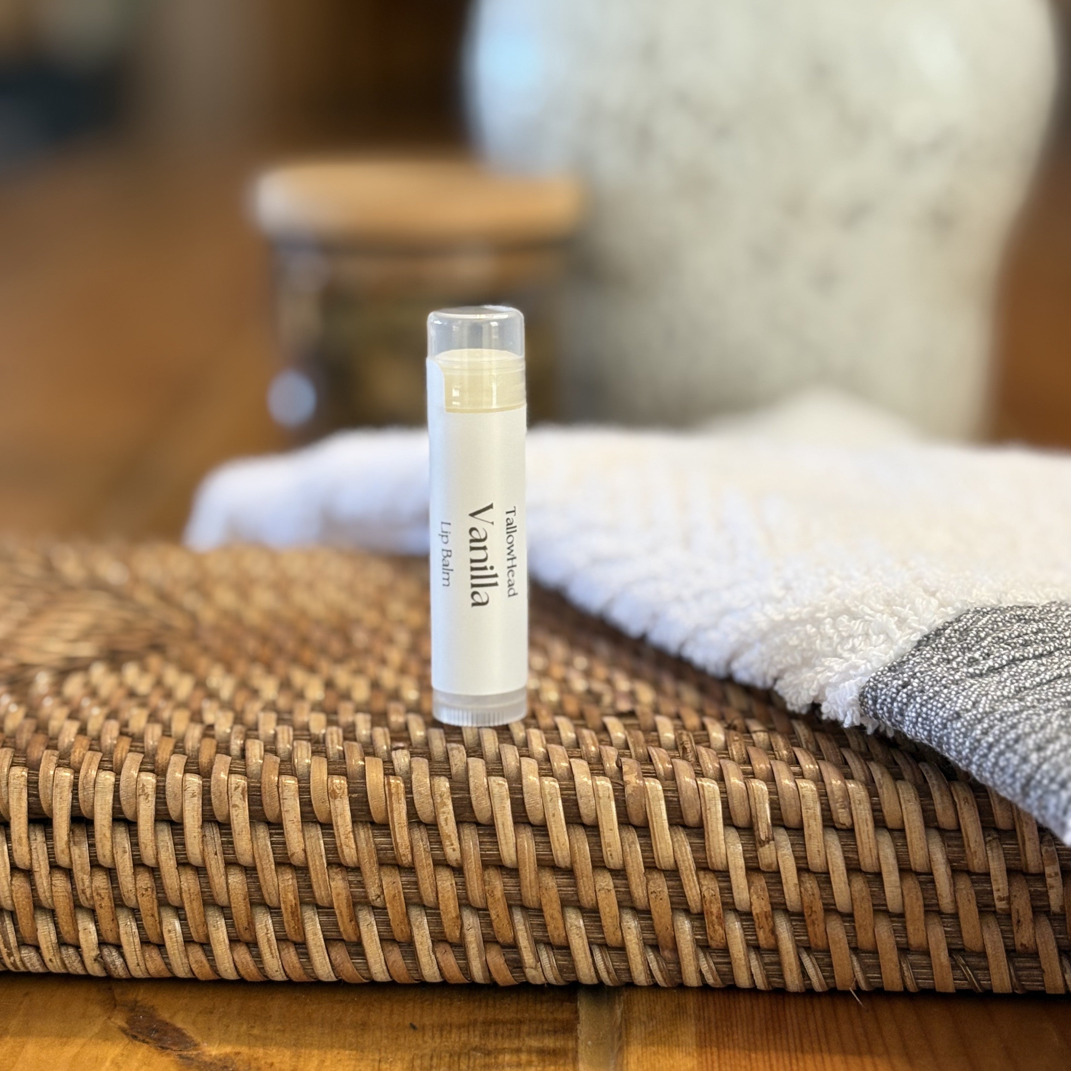 Vanilla-scented lip balm on a woven surface with a blurred background