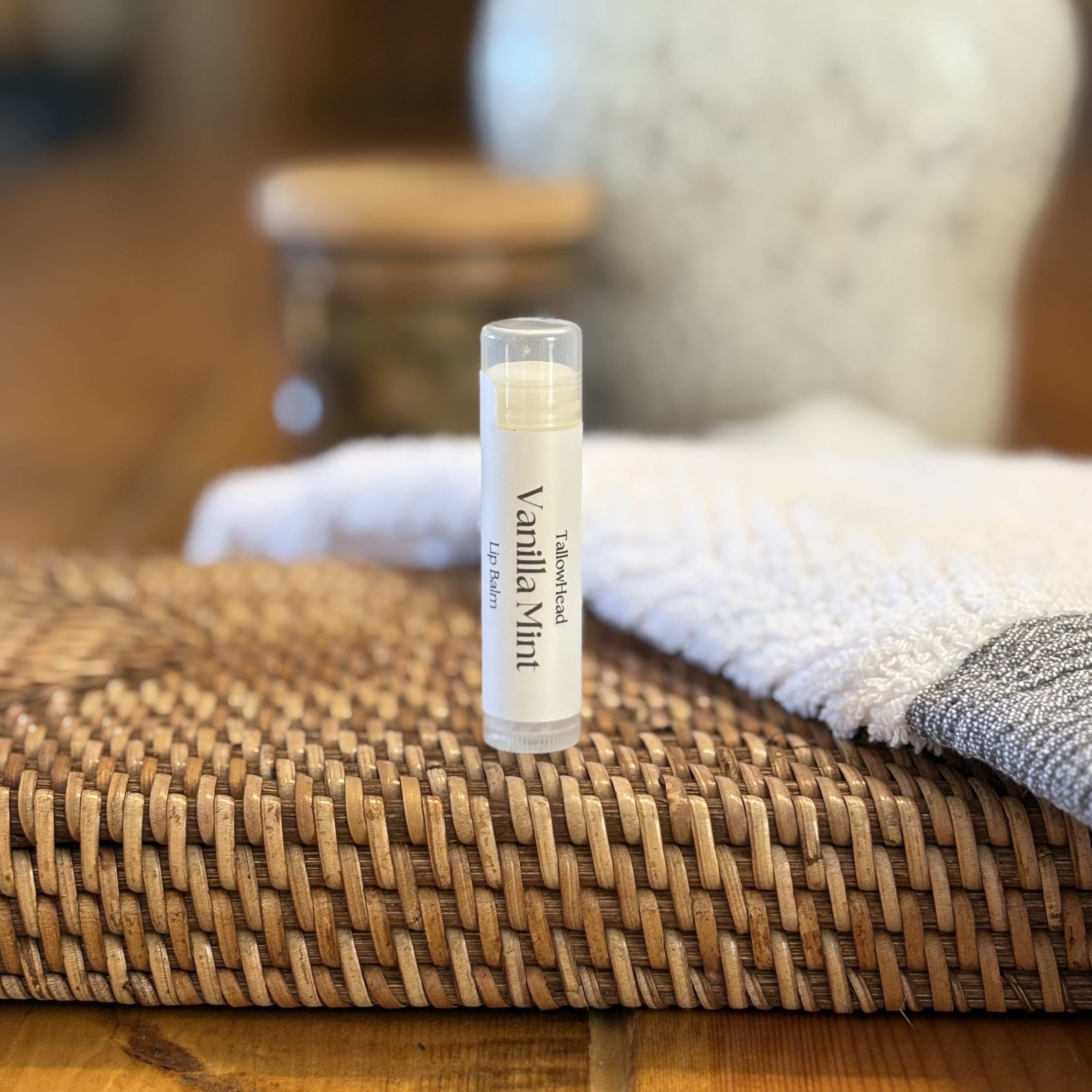 Vanilla Mint lip balm on a woven mat with a blurred background